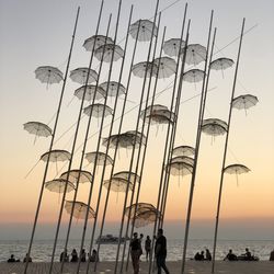 People on beach against sky during sunset