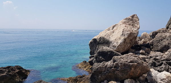 Scenic view of rocks by sea against sky