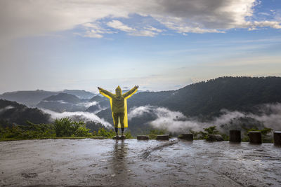 Rear view of woman standing by mountain against sky