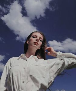 Low angle view of woman looking at camera against sky