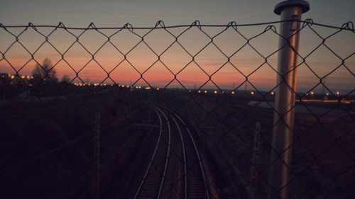 Chainlink fence against sky during sunset