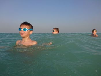 Portrait of shirtless boy swimming in sea against clear sky