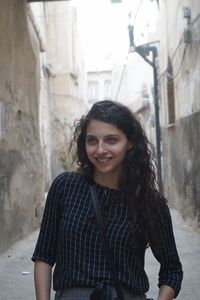 Portrait of smiling young woman standing against wall