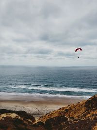 Scenic view of a paraglider floating in the sky above the cliffs and sea 