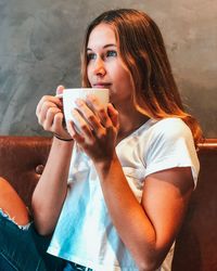 Young woman looking away while holding coffee cup