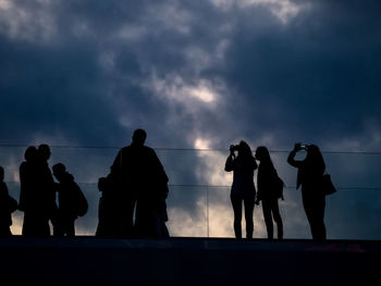 Low angle view of silhouette people standing against sky