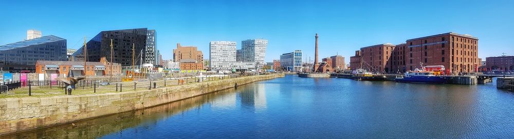 Canal amidst buildings in city against clear blue sky