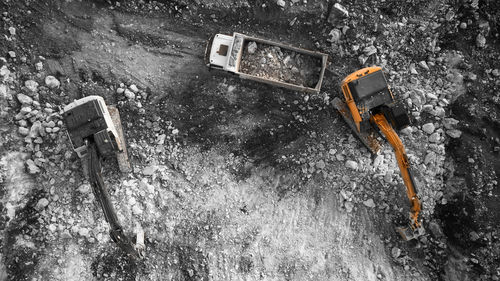 Top down aerial view of excavator loading tipper truck with crushed rock soil. 