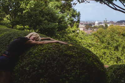 Young woman lying on hedge