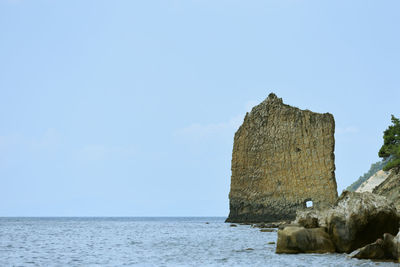 Built structure on rocks by sea against sky