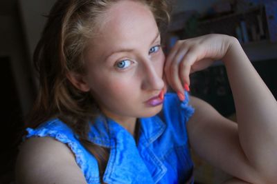 Portrait of young woman with orange nail polish sitting at table