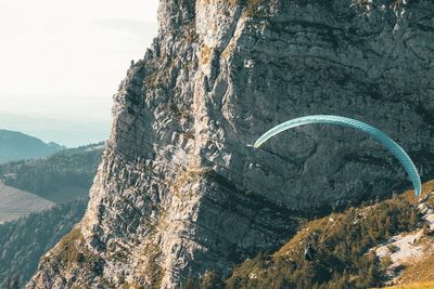 High angle view of man paragliding by mountains against sky