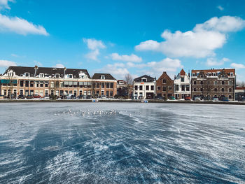 Buildings by houses against blue sky during winter