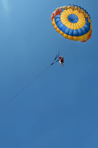 Low angle view of person paragliding against clear blue sky