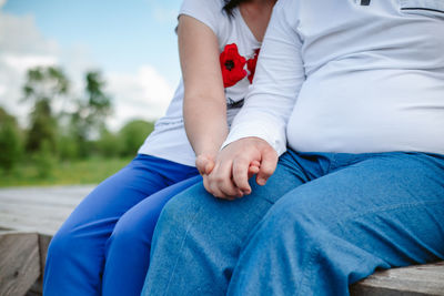 Midsection of couple sitting against blue wall