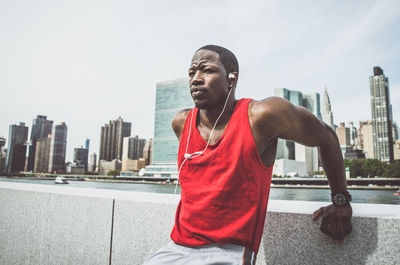 Young man looking away against buildings in city