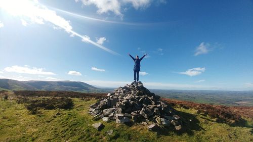 Woman standing with raised hands against sky