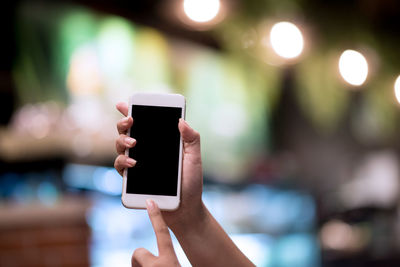 Close-up of human hand holding smart phone in city at night