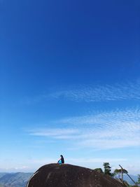 Man standing on mountain against blue sky