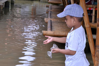 Boy feeding fish in pond