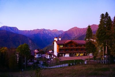 Houses by trees and mountains against clear sky