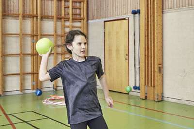 Girl throwing ball in pe class in school gym