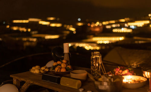 Lit tea light candles on table at restaurant at night