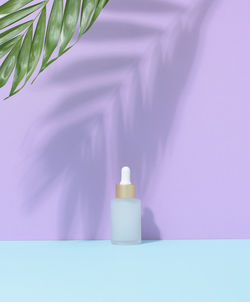 White glass bottle with a pipette. purple background. containers for cosmetics, oils, serum