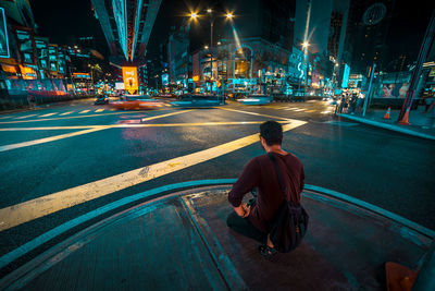 Rear view of man on illuminated city street at night