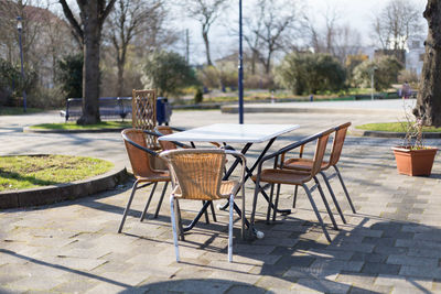 Wicker stack chairs or garden chairs at an outdoor table in sunny weather