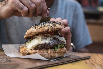 Close-up of hand holding burger on table