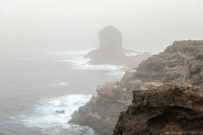 Rock formation in sea against sky