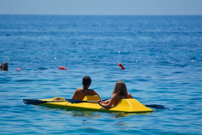 Rear view of women canoeing on sea