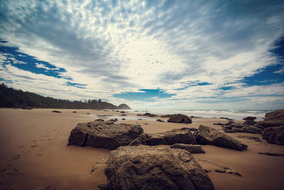 Scenic view of beach against cloudy sky