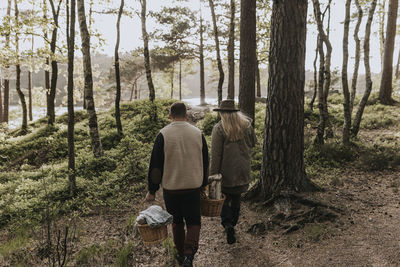 Rear view of couple walking through forest