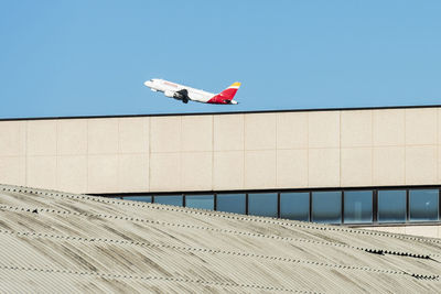 Low angle view of airplane flying against clear blue sky