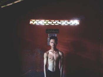 Young man standing against illuminated wall