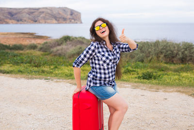 Portrait of young woman wearing sunglasses standing on land