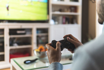 Young male gamer playing video game at home