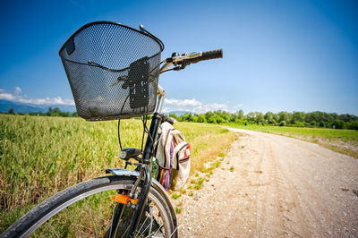 Bicycle on field by road against sky