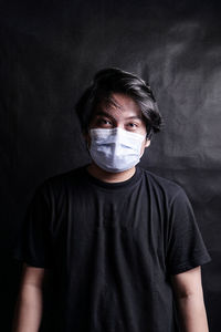 Portrait of man wearing mask standing against wall