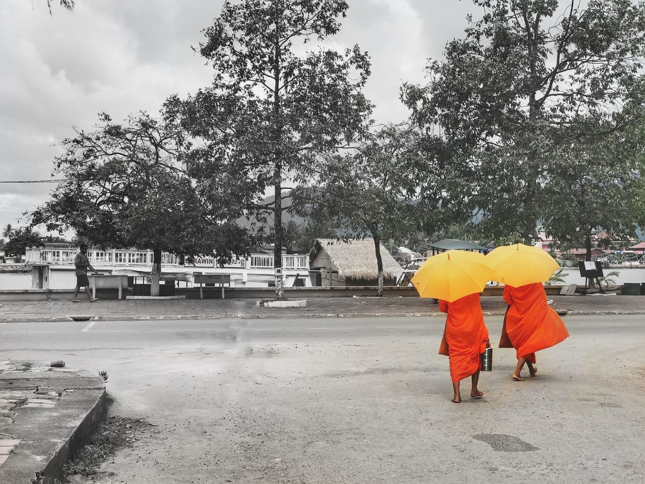 REAR VIEW OF PEOPLE WALKING ON ROAD AGAINST SKY