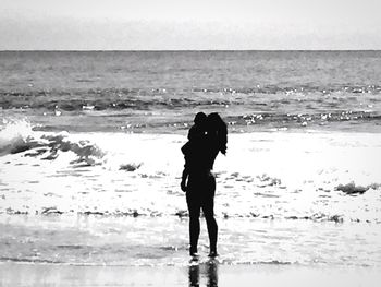 Silhouette woman standing on beach against sky