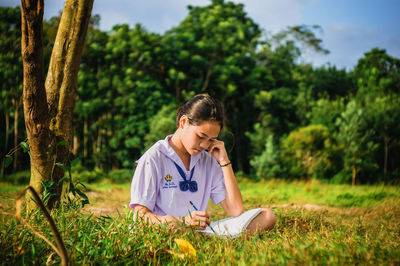 Girl studying on grassy field