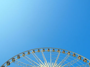 Cropped image of ferris wheel against clear blue sky