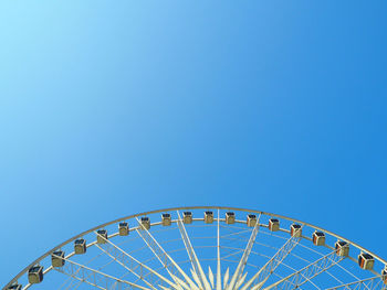 Low angle view of ferris wheel against blue sky