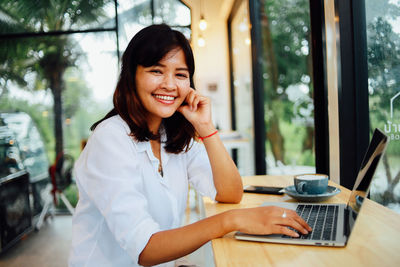 Portrait of smiling businesswoman using technology at cafe