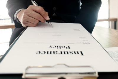 Midsection of person holding paper with text on table