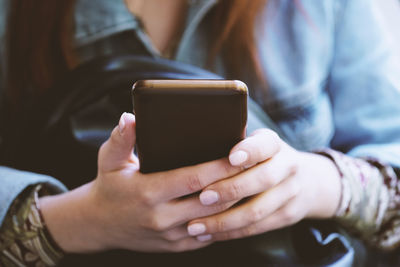 Hands of unrecognizable young woman using smartphone or mobile phone