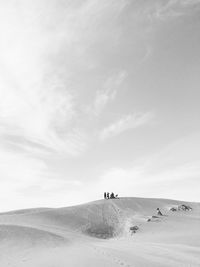 People on shore against sky